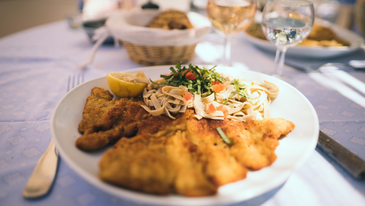 Elegantly served pork schnitzel with a small side dish.