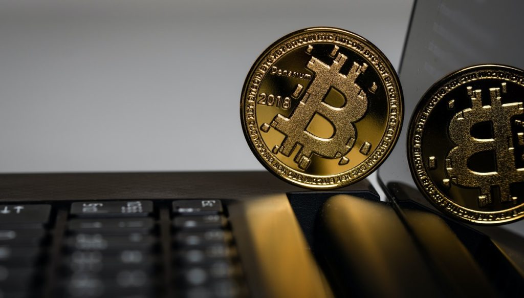 Bitcoin, czyli moneta BTC umieszczona nad klawiaturą laptopa.