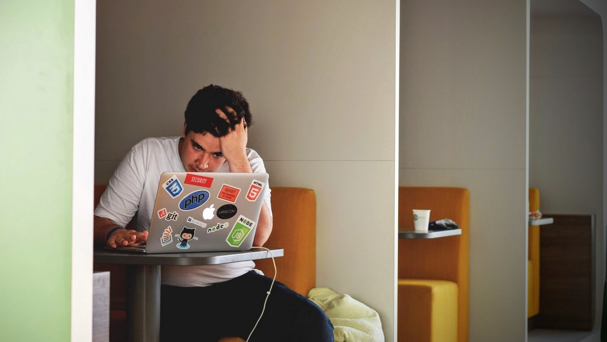 En ung mand med en bærbar computer, hvis største problem er økonomisk stress.
